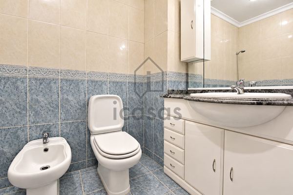 Casa de banho com móvel de lavatório, sanita e bidé, em azulejo azul e bege
