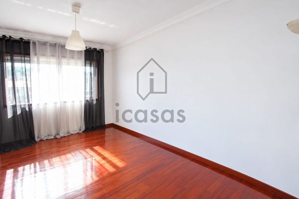 Divisão vazia com janela ampla, cortinados e soalho de madeira