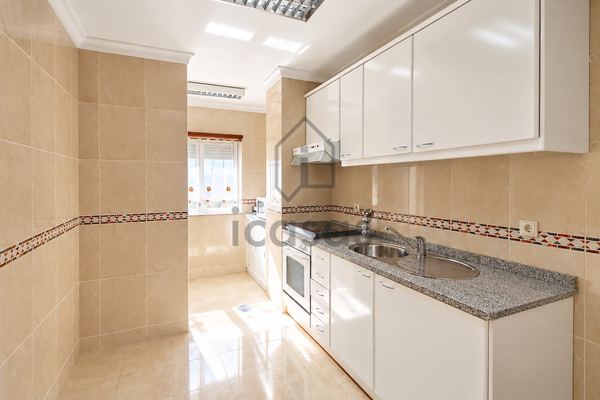 Cozinha com armários brancos, bancada em granito e janela